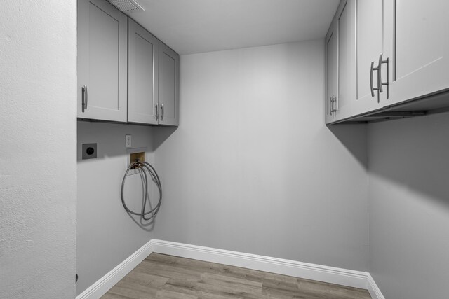 laundry area featuring cabinets, electric dryer hookup, washer hookup, and light hardwood / wood-style floors