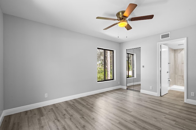 unfurnished bedroom featuring connected bathroom, a closet, light wood-type flooring, and ceiling fan