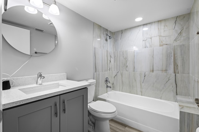 full bathroom with vanity, hardwood / wood-style floors, tiled shower / bath combo, and toilet