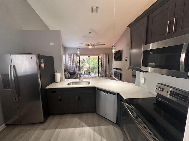 kitchen featuring sink, vaulted ceiling, kitchen peninsula, stainless steel appliances, and light hardwood / wood-style floors