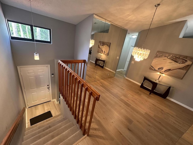 stairway with hardwood / wood-style flooring, a notable chandelier, and a textured ceiling