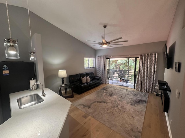 living room featuring vaulted ceiling, sink, ceiling fan, and light hardwood / wood-style flooring