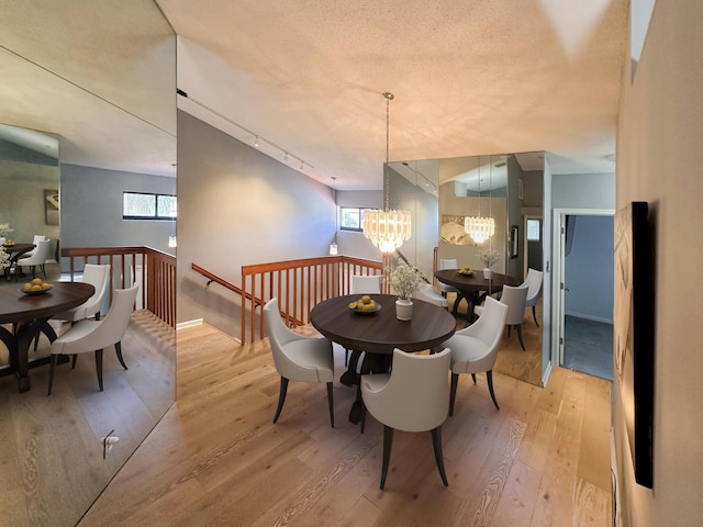 dining room with a notable chandelier, track lighting, light hardwood / wood-style floors, and a textured ceiling