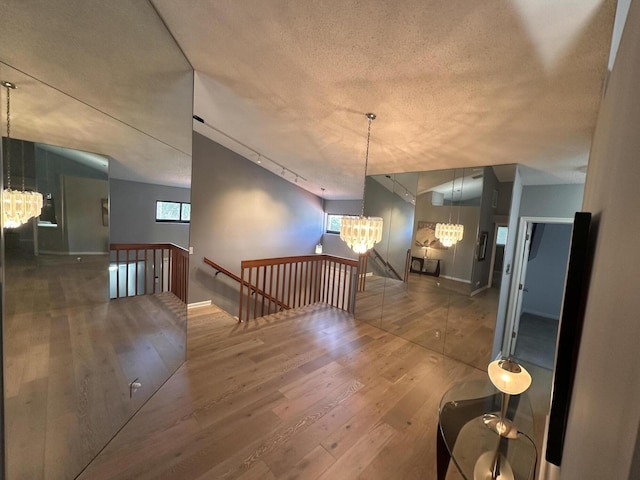 interior space with dark hardwood / wood-style floors, track lighting, a notable chandelier, and a textured ceiling