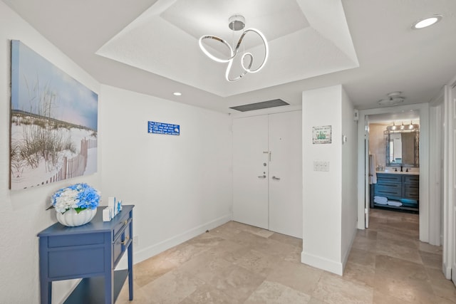 tiled foyer with a chandelier and a tray ceiling