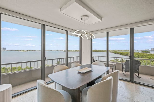 sunroom / solarium featuring an inviting chandelier and a water view