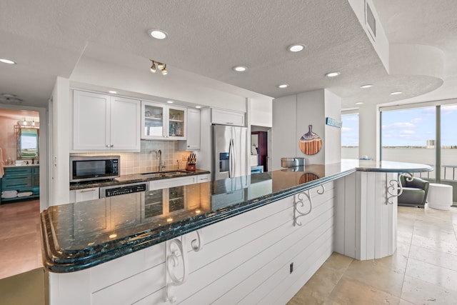 kitchen featuring light tile patterned flooring, white cabinetry, decorative backsplash, appliances with stainless steel finishes, and a textured ceiling