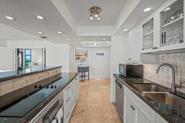 kitchen featuring light tile patterned flooring, tasteful backsplash, a tray ceiling, white cabinets, and sink