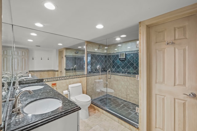 bathroom with walk in shower, dual bowl vanity, toilet, tile walls, and tile patterned floors