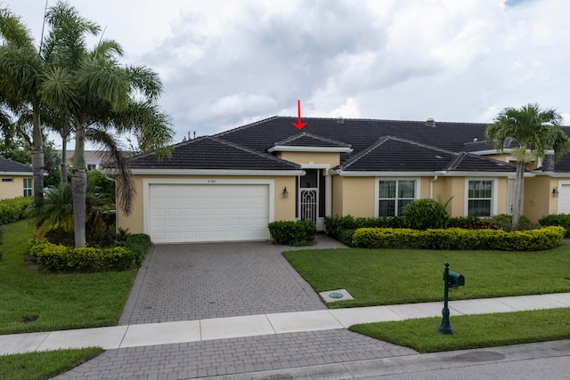 ranch-style home with a garage and a front lawn