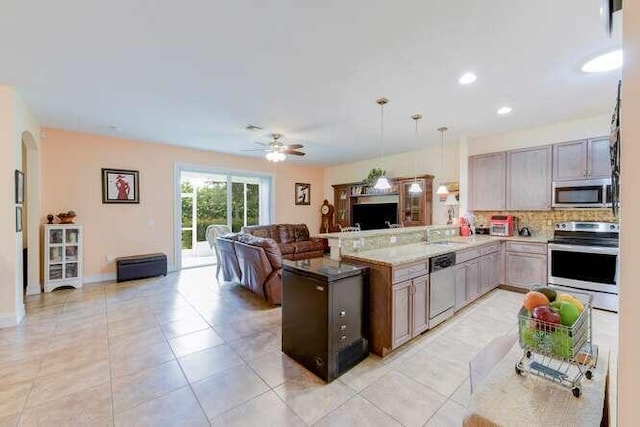 kitchen with decorative light fixtures, tasteful backsplash, appliances with stainless steel finishes, open floor plan, and a peninsula