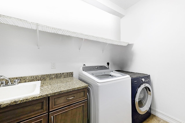 laundry room featuring washing machine and dryer, a sink, cabinet space, and baseboards