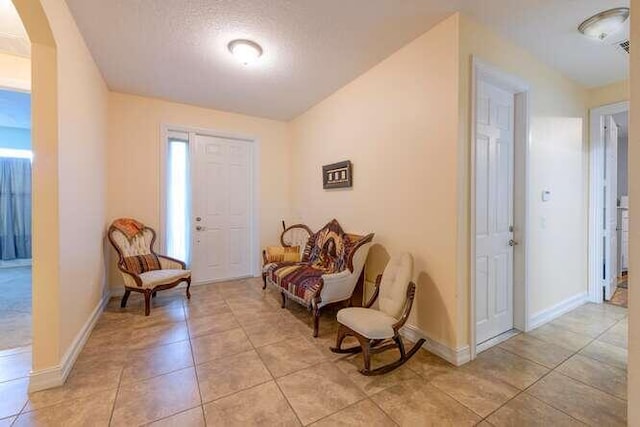 entryway featuring baseboards, a textured ceiling, and light tile patterned flooring