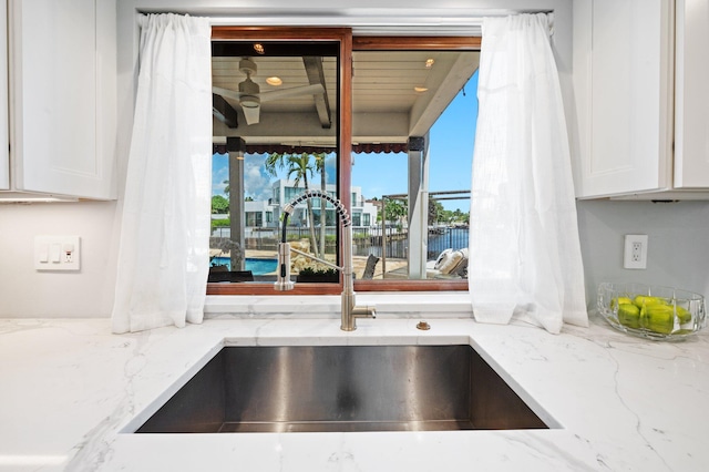 details featuring white cabinets, sink, and light stone counters