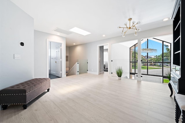 interior space featuring a notable chandelier, light wood-type flooring, and a skylight