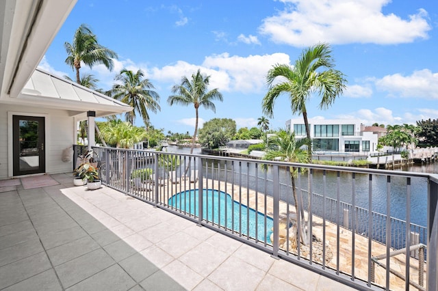 balcony with a water view and a fenced in pool