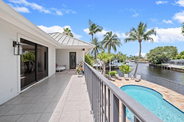 balcony featuring a patio, a water view, and a fenced in pool