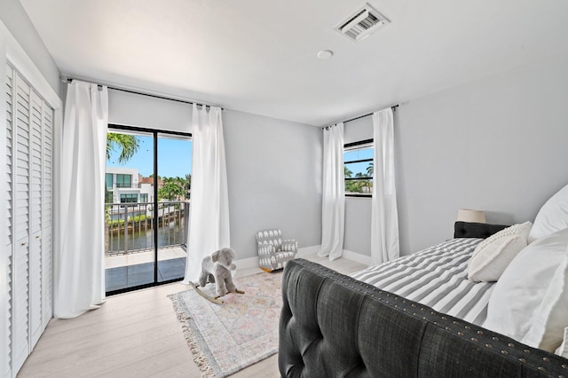 bedroom with access to exterior, light wood-type flooring, and multiple windows