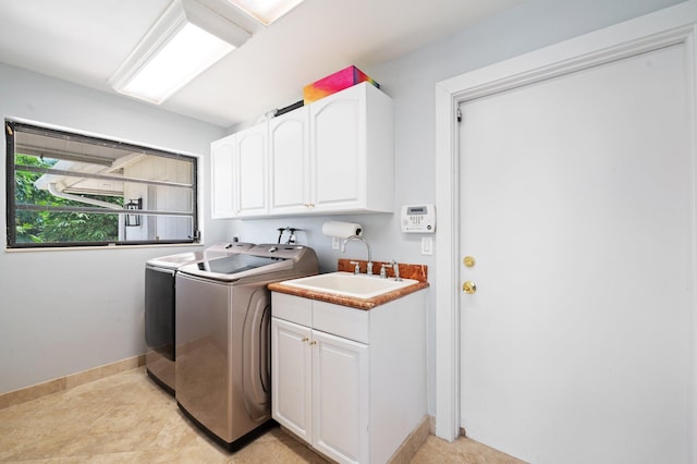 laundry area with cabinets, light tile patterned floors, washer and dryer, and sink