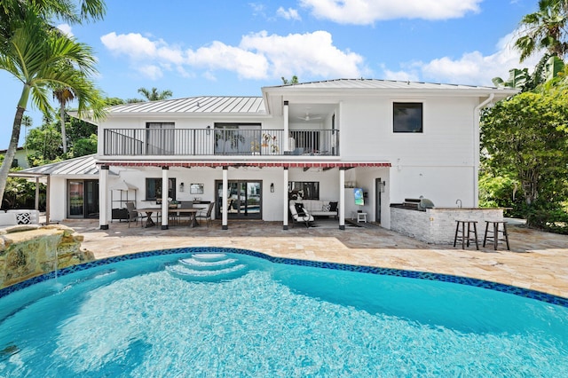 back of property featuring exterior bar, a patio area, and a balcony