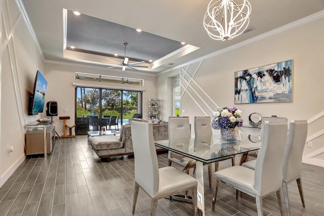 dining room with a raised ceiling, crown molding, and ceiling fan with notable chandelier