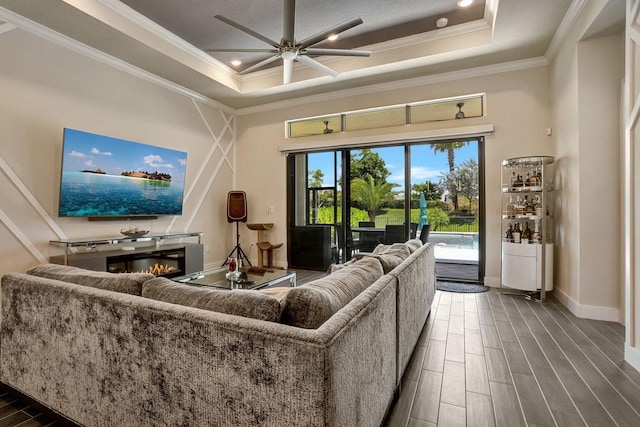 living room featuring crown molding, dark hardwood / wood-style floors, and a raised ceiling