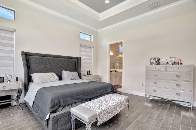 bedroom featuring multiple windows, a tray ceiling, ensuite bath, and ornamental molding