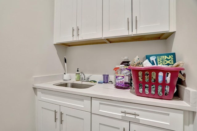 bar with light stone counters, sink, and white cabinets