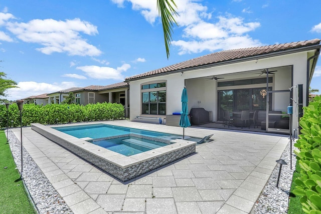 rear view of house featuring a patio area, ceiling fan, and an in ground hot tub