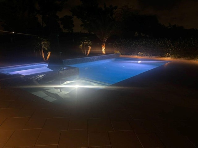 pool at twilight with a patio area