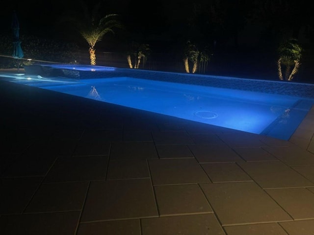 view of pool at twilight