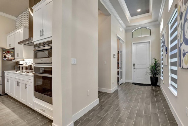 entryway with ornamental molding, a towering ceiling, and a tray ceiling