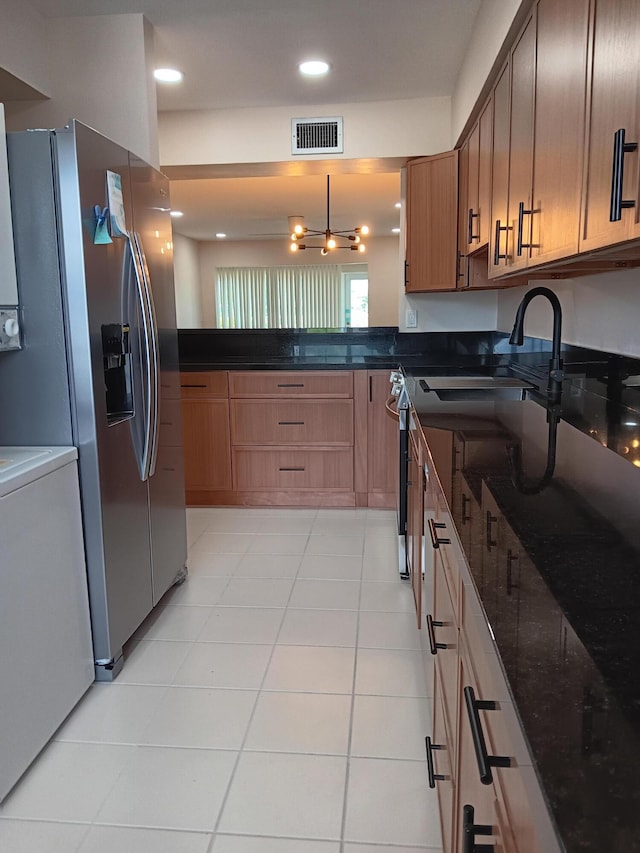 kitchen with dark stone counters, light tile patterned flooring, sink, and stainless steel fridge with ice dispenser