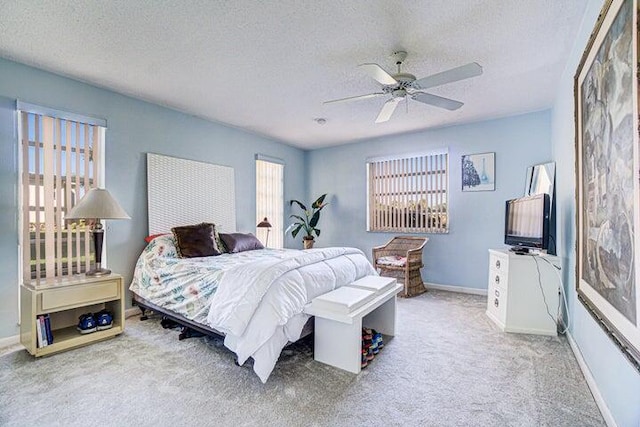 carpeted bedroom featuring ceiling fan and a textured ceiling