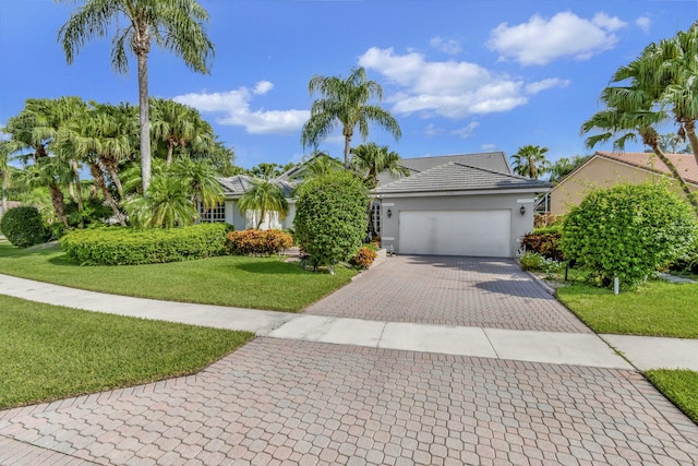 view of front of property with a garage, a front yard, decorative driveway, and stucco siding