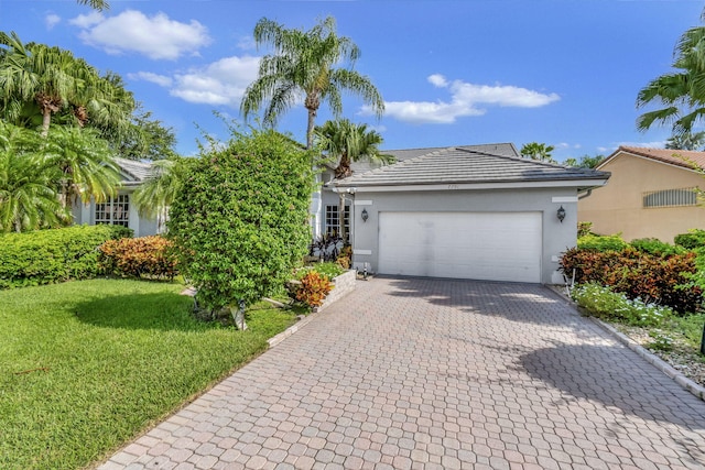 view of front of house featuring a garage, decorative driveway, a front yard, and stucco siding