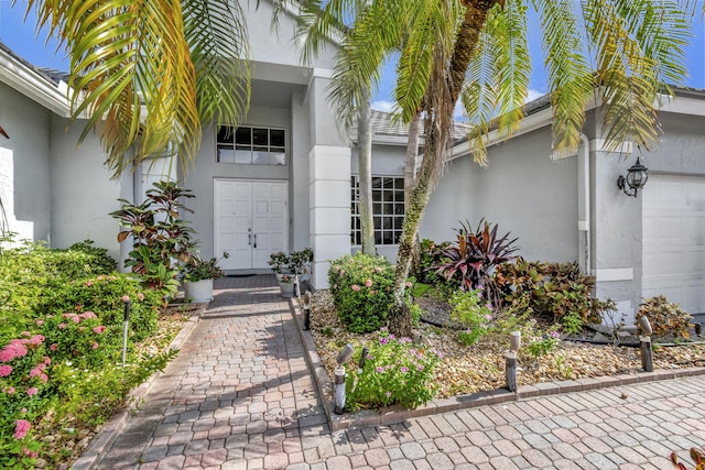 property entrance featuring a garage and stucco siding