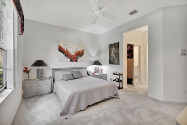 bedroom featuring light colored carpet, ensuite bath, and ceiling fan