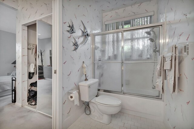 bathroom with tile patterned flooring, bath / shower combo with glass door, and toilet