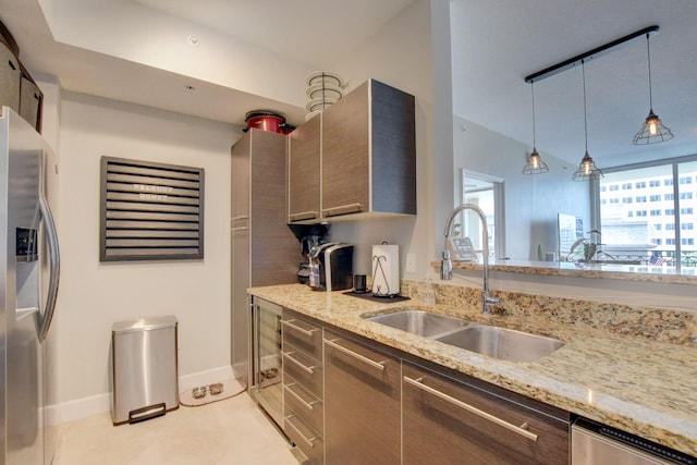 kitchen with sink, hanging light fixtures, stainless steel appliances, and light stone counters