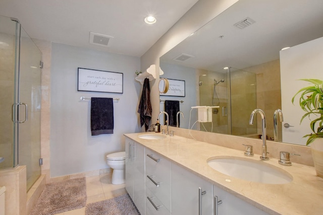 bathroom featuring vanity, a shower with door, toilet, and tile patterned floors