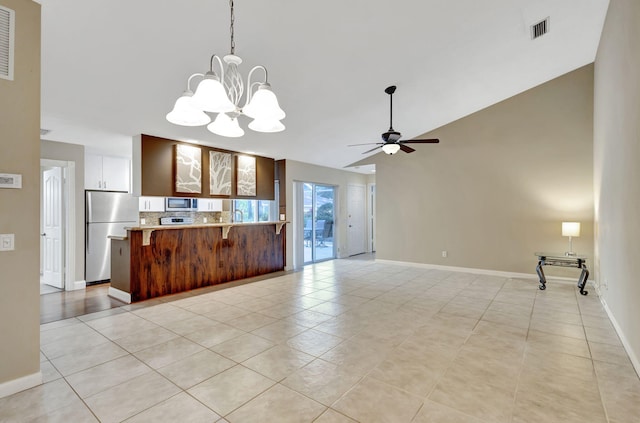 kitchen featuring backsplash, ceiling fan with notable chandelier, stainless steel appliances, light tile patterned floors, and hanging light fixtures