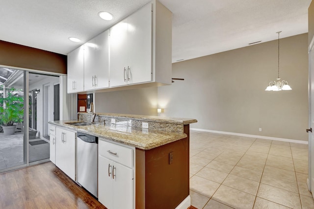 kitchen with white cabinets, kitchen peninsula, stainless steel dishwasher, and hanging light fixtures