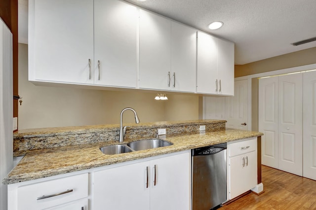 kitchen featuring light wood-type flooring, light stone counters, stainless steel dishwasher, sink, and white cabinets