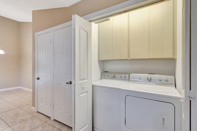 washroom featuring washing machine and dryer, light tile patterned floors, and cabinets