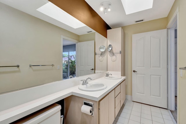 bathroom featuring a skylight, tile patterned flooring, vanity, and toilet