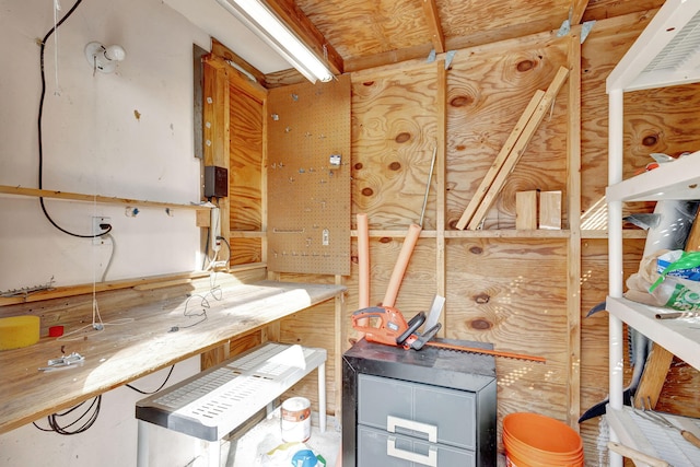 miscellaneous room with a workshop area and wood walls