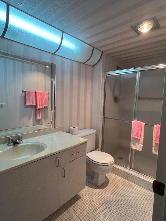 bathroom with vanity, walk in shower, tile patterned flooring, and toilet