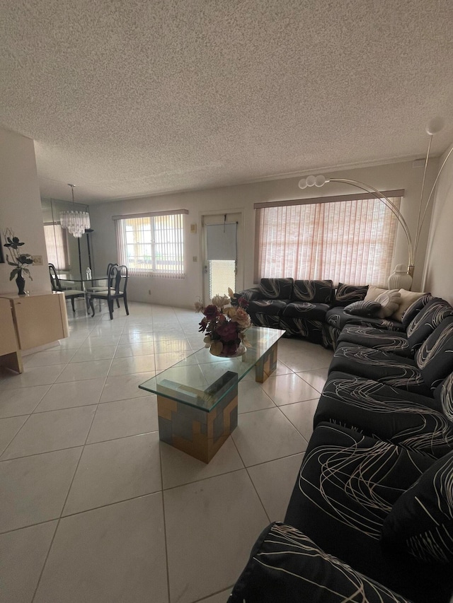 living room with light tile patterned flooring, a notable chandelier, and a textured ceiling