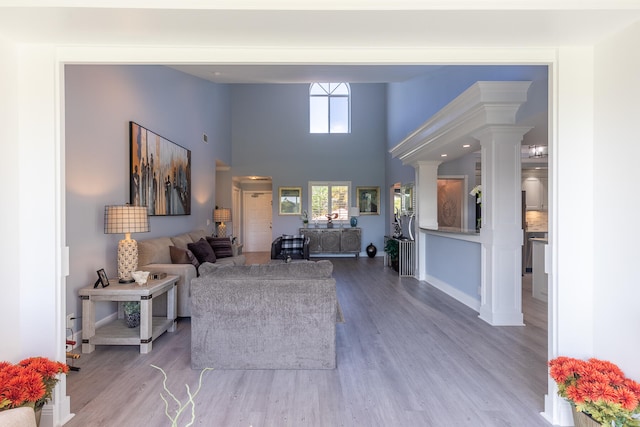 living room with ornate columns, hardwood / wood-style floors, and a towering ceiling